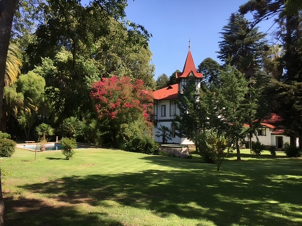 Scenic view of the Baron Knyphausen Vineyard estate, featuring a historic white manor with red rooftops, surrounded by lush greenery and vibrant trees.