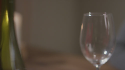 Close-up video of rich red wine being poured from a bottle into a clear wine glass, set against a softly lit background.